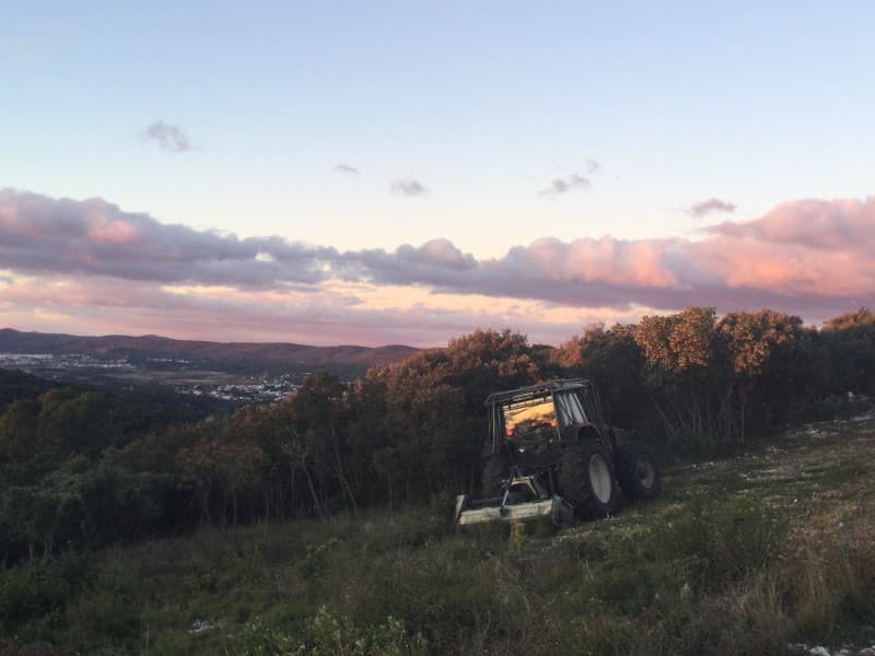 Tracteur et broyeur Majuro débroussaillant une crête de garrigue au coucher du soleil à Murles
